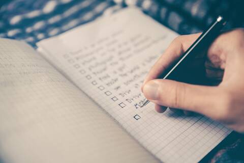 Eine Person schreibt eine Checkliste.