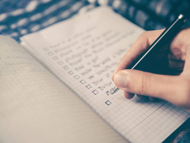 Eine Person schreibt eine Checkliste.